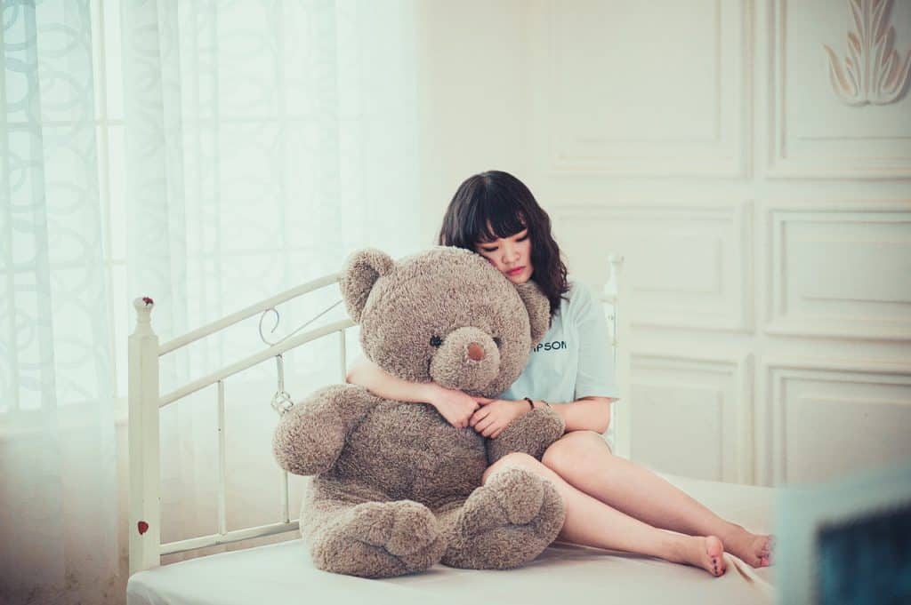 נערה על המיטה עם דובי